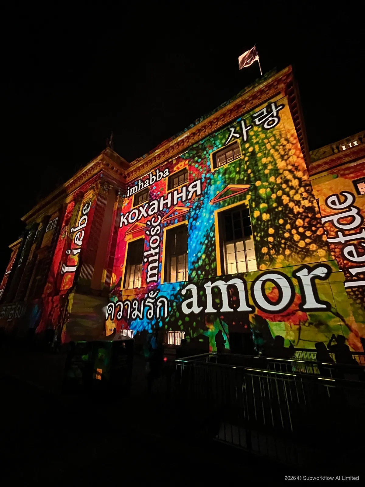 A building lit with projected words for love in many languages, “amor” the largest