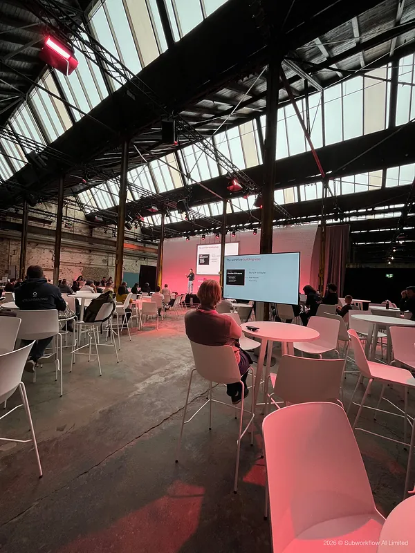 Seats around a side stage, with “The workflow building loop” on the screens