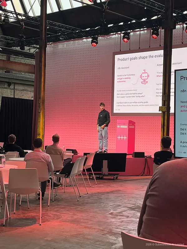 A speaker on stage beside a slide headed “Product goals shape the evaluation”
