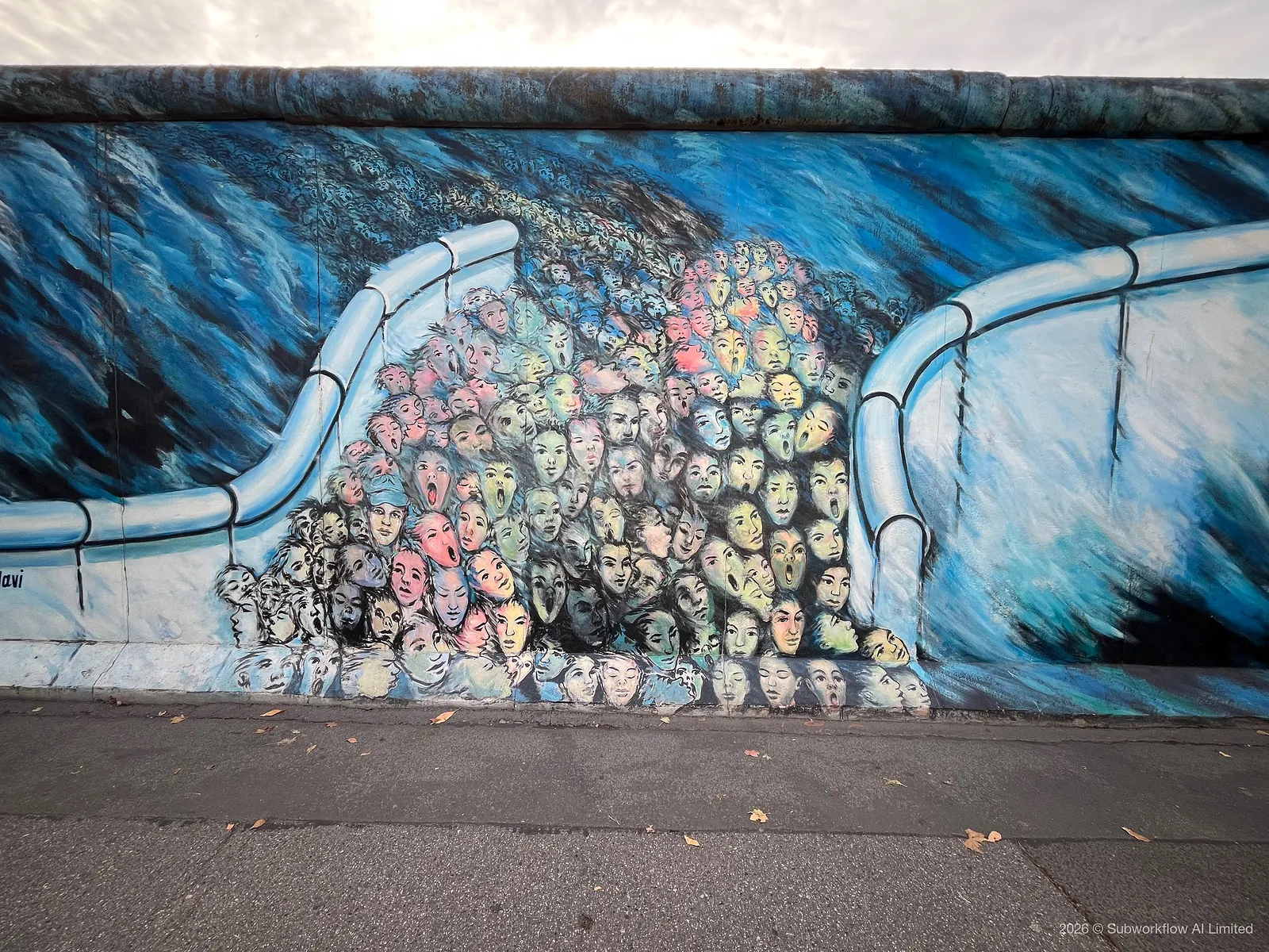 An East Side Gallery mural of a crowd of faces pouring through a gap in the Wall